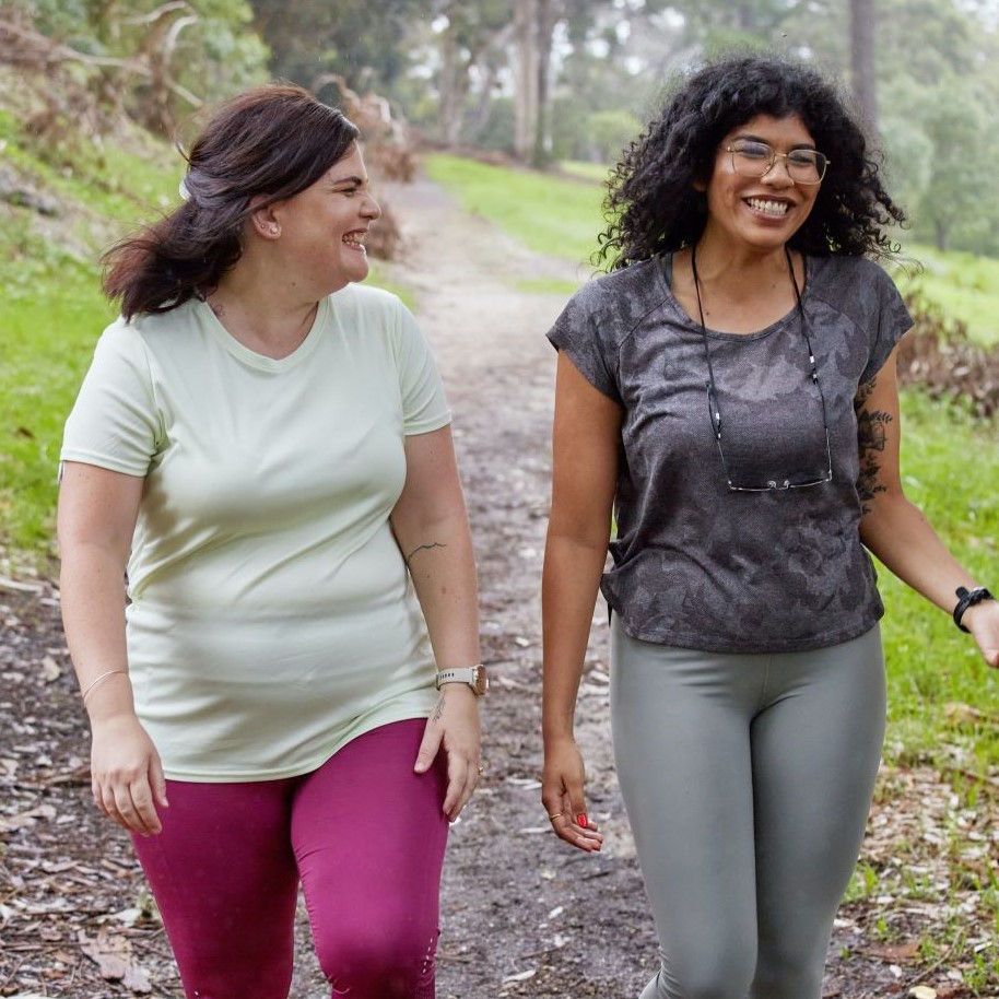 Two women walk through the forest discussing mental health adult services.
