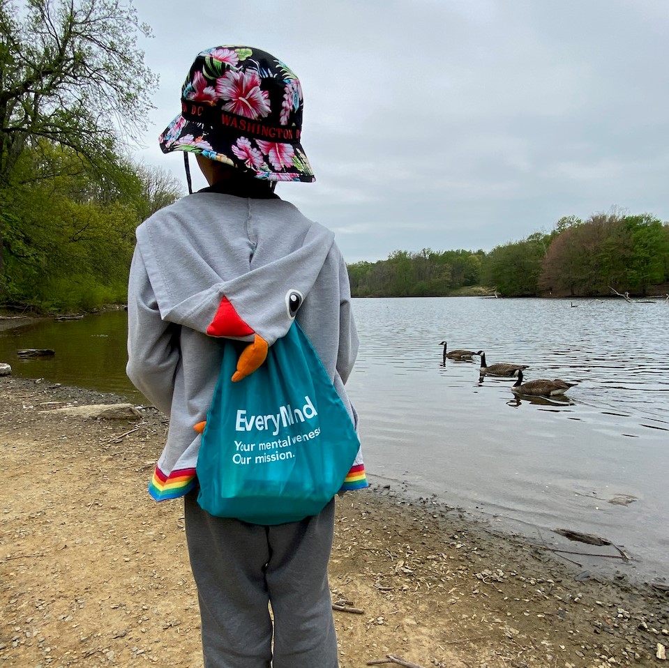 A child receiving youth & family services stands on a lakeshore.
