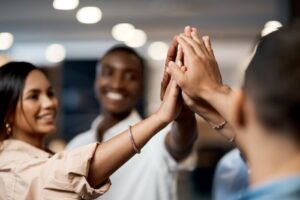 Group of interns smile and give each other a high five in an office.