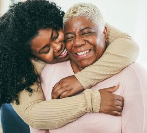 young woman hugs her mother in a warm embrace and smile, representing EveryMind home page
